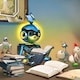 A robot sits at a desk with books and toys.